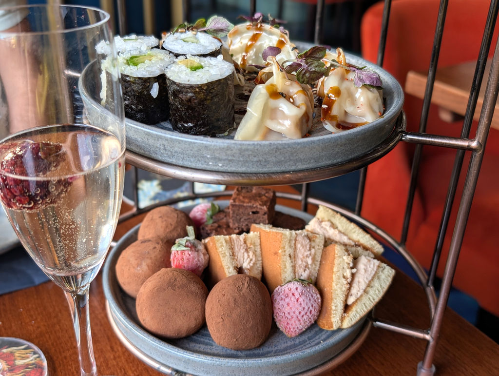 Two tiers of a Japanese tea with sushi and gyoza on the top tier.