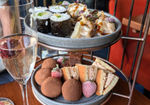 Two tiers of a Japanese tea with sushi and gyoza on the top tier.