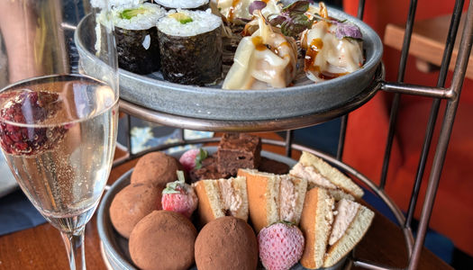 Two tiers of a Japanese tea with sushi and gyoza on the top tier.