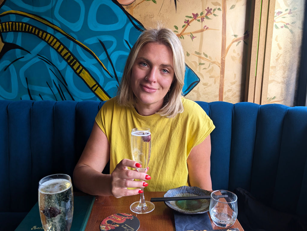 Mari in a yellow top with a glass of prosecco at Blossoms Brighton
