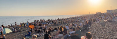 Summer on the beach with a crowd of people sitting on the stones.