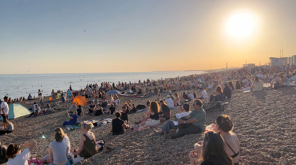 Summer on the beach with a crowd of people sitting on the stones.