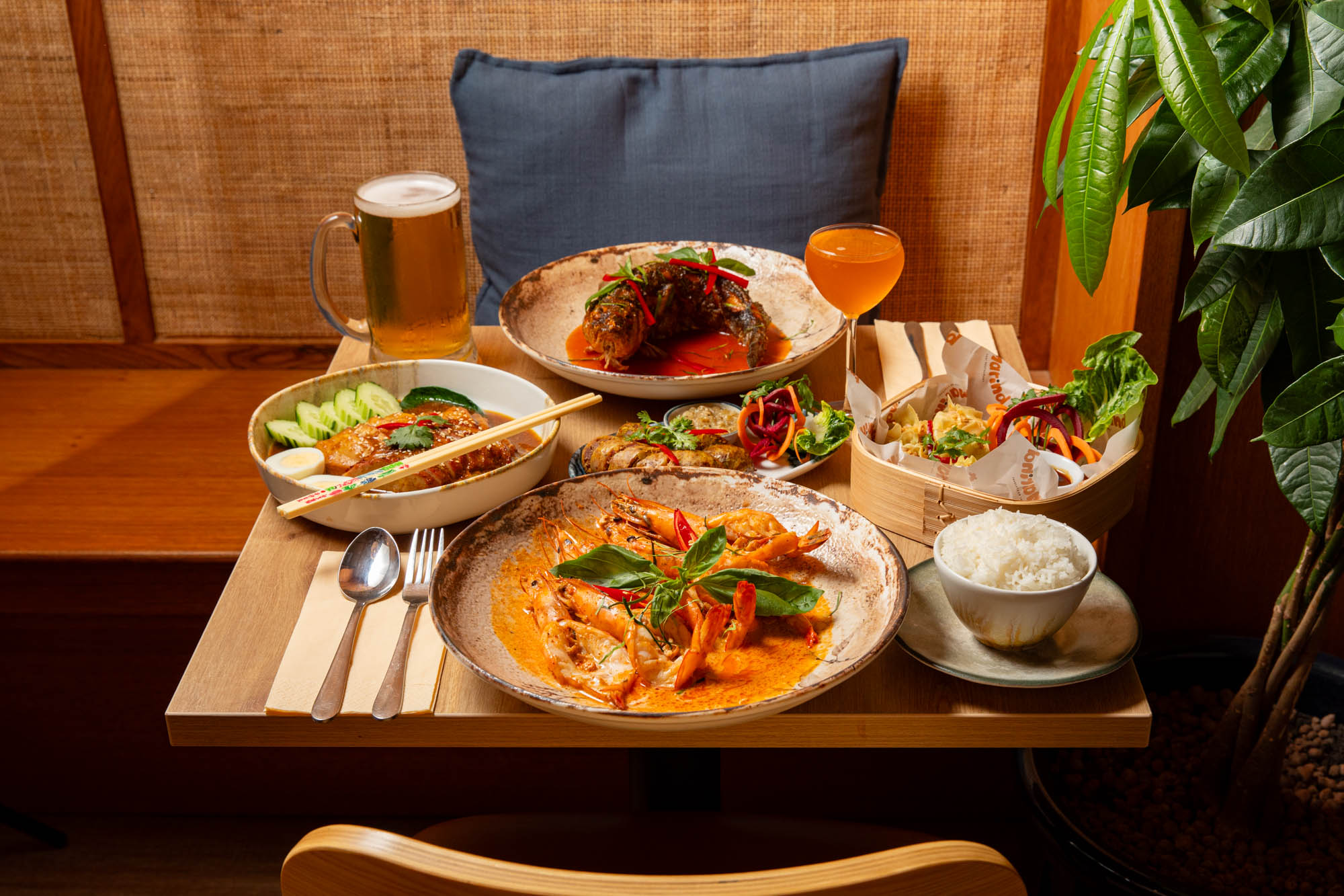 close up shot of the wooden table laid out with few plates with dishes and couple of drinks at Tamarind