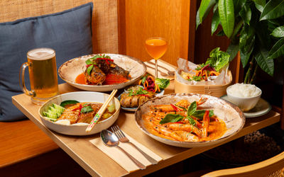 close up shot of the wooden table laid out with few plates with dishes and couple of drinks at Tamarind
