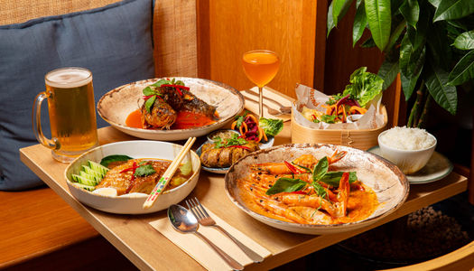 close up shot of the wooden table laid out with few plates with dishes and couple of drinks at Tamarind