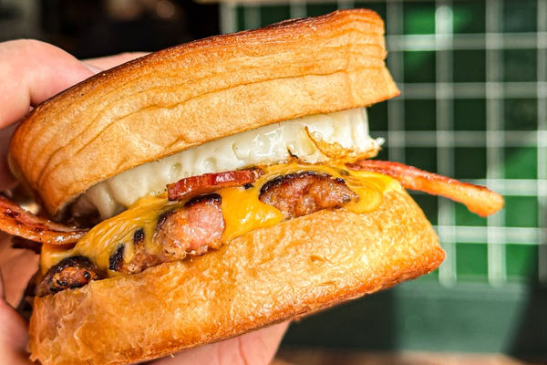 A croissant bun filled with egg, cheese, bacon and sausage