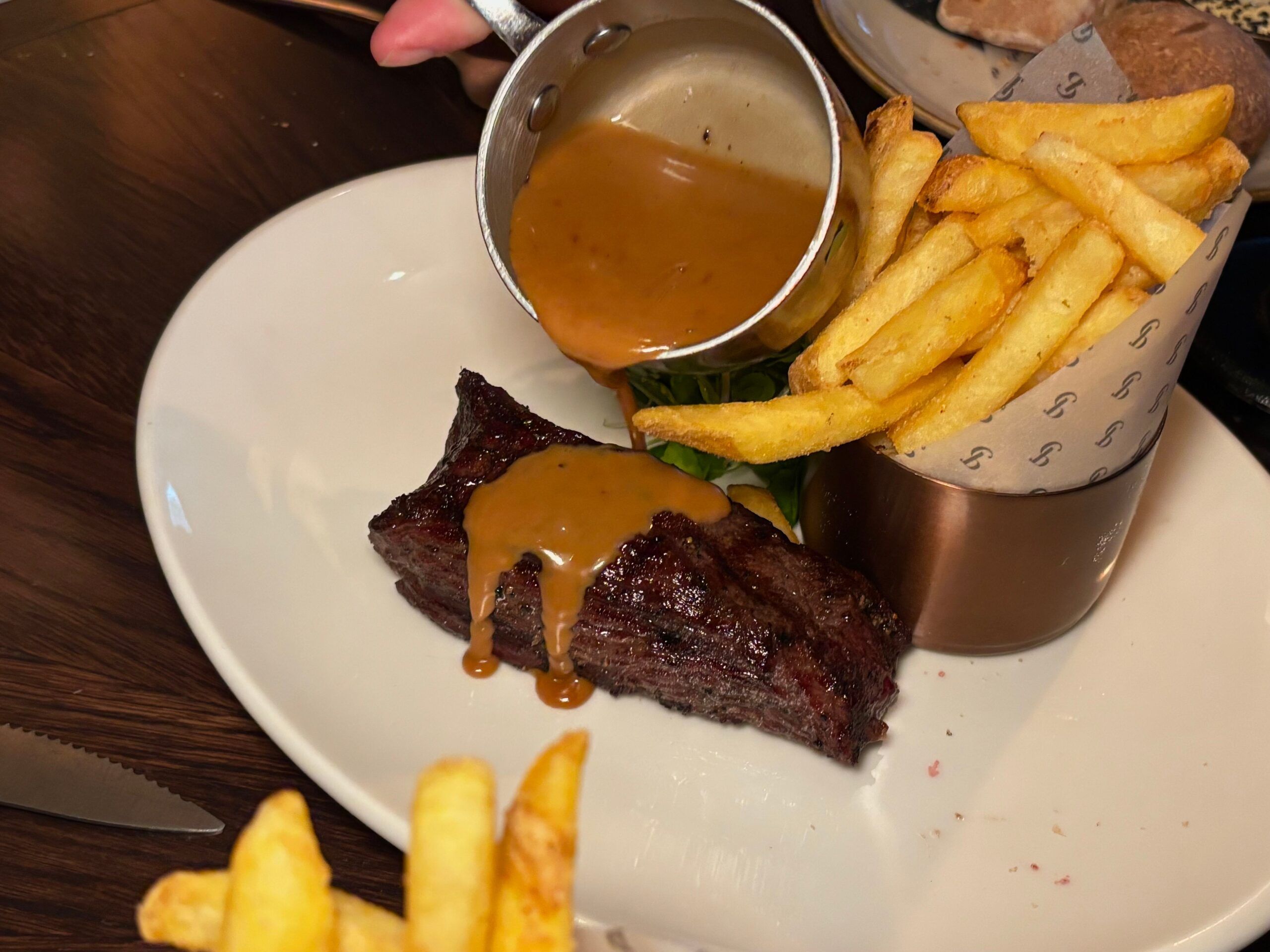 pouring gravy on the steak served with chips