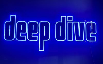 The neon sign for Deep Dive Bar in Brighton. Bright blue.