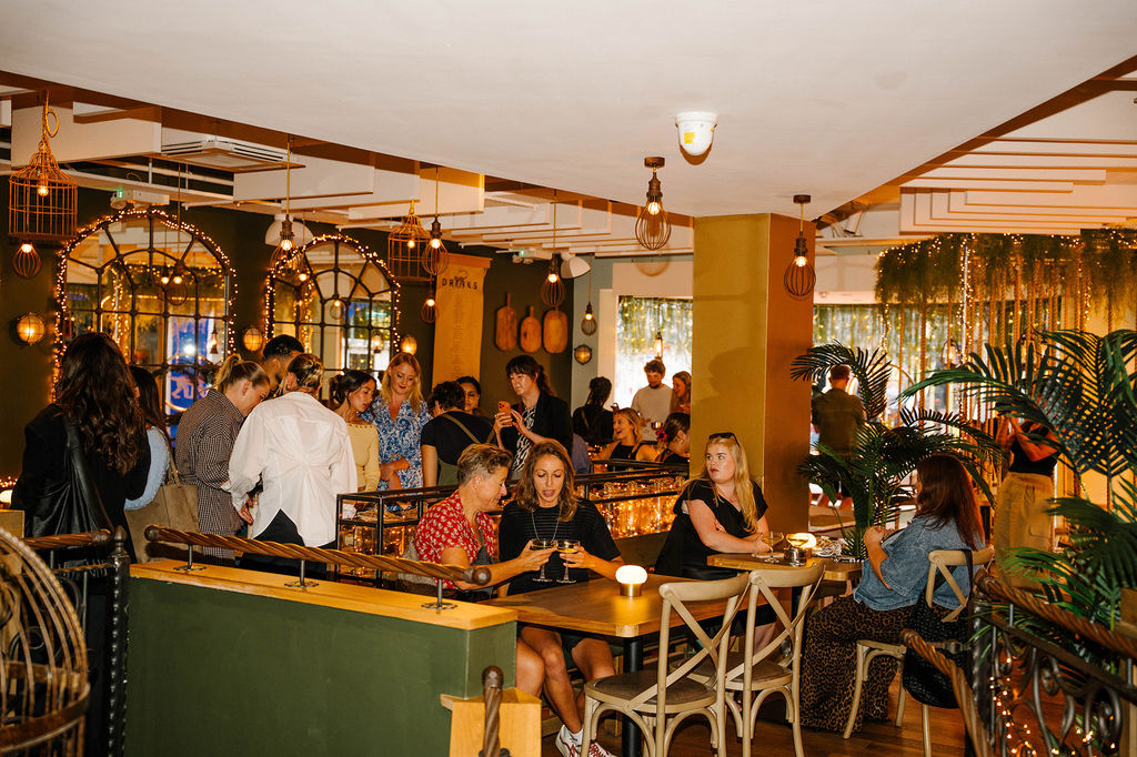 A busy restaurant launch event with people drinking andn eating standing and sitting at Mowgli Brighton