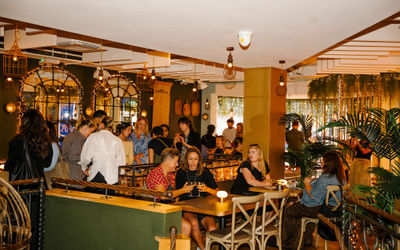 A busy restaurant launch event with people drinking andn eating standing and sitting at Mowgli Brighton