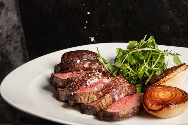 a steak on a plate being salted at Chez Mal in Brighton