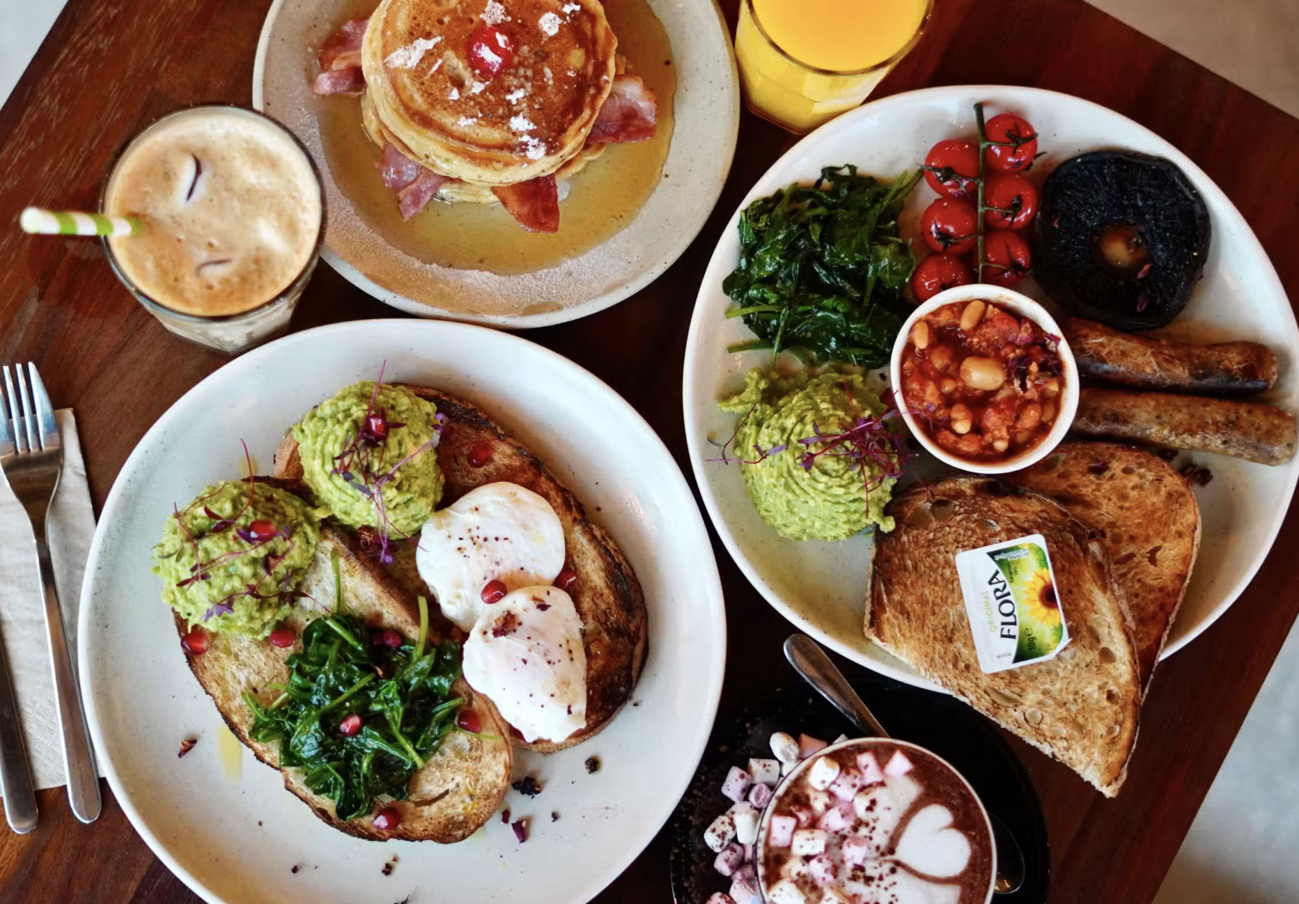 Brunch spread with avocado on sourdough, poached eggs, bacon pancakes, a full breakfast, iced coffee and hot chocolate