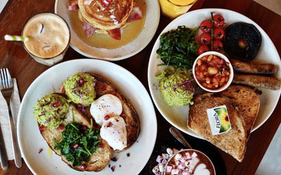 Brunch spread at North Laine Cafe Brighton with avocado on sourdough, poached eggs, bacon pancakes, a full breakfast, iced coffee and hot chocolate
