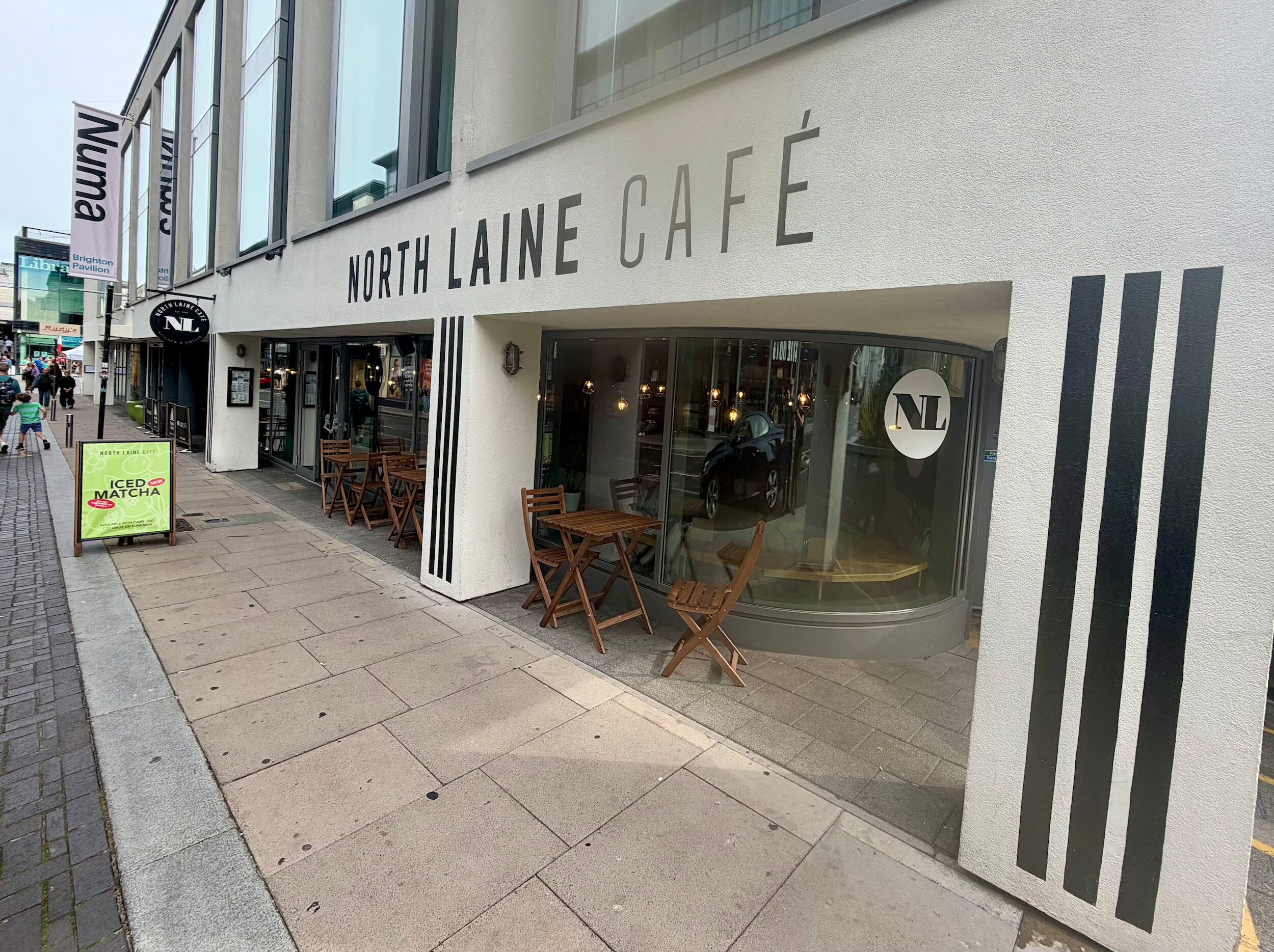 North Laine Café on a Brighton street corner, with wooden tables and chairs on the wide pavement and a chalkboard sign outside
