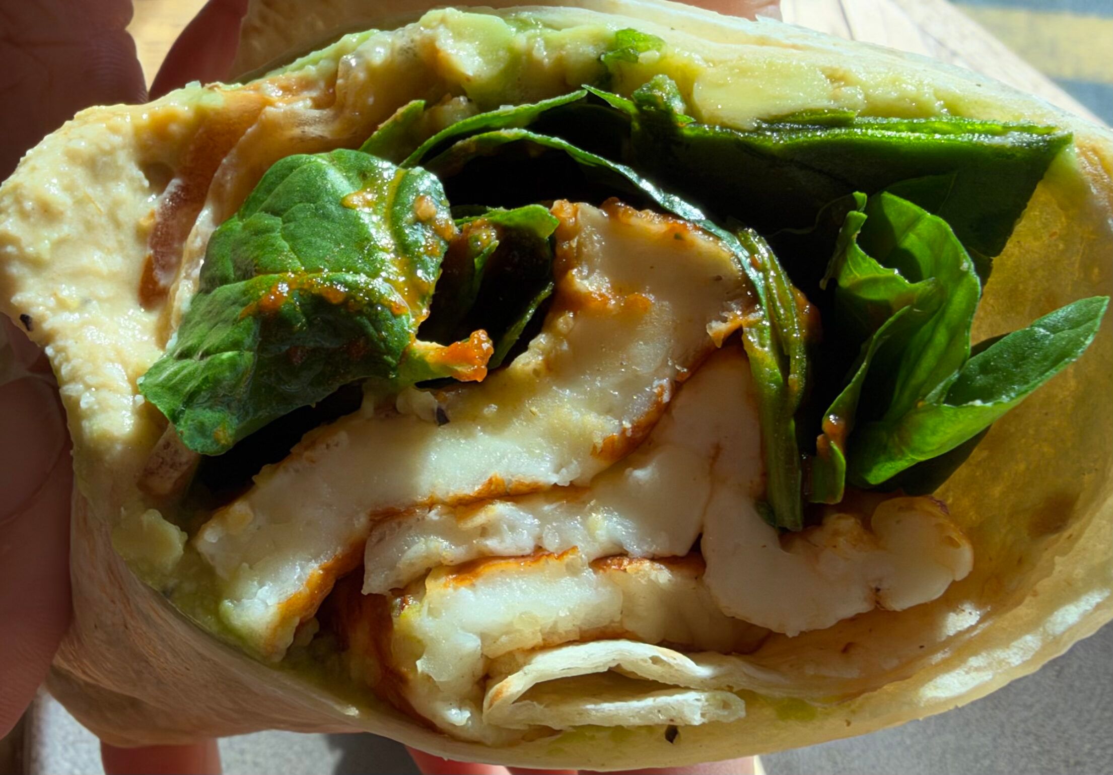 Close-up of a halloumi wrap filled with grilled halloumi and fresh spinach leaves at North Laine Café in Brighton