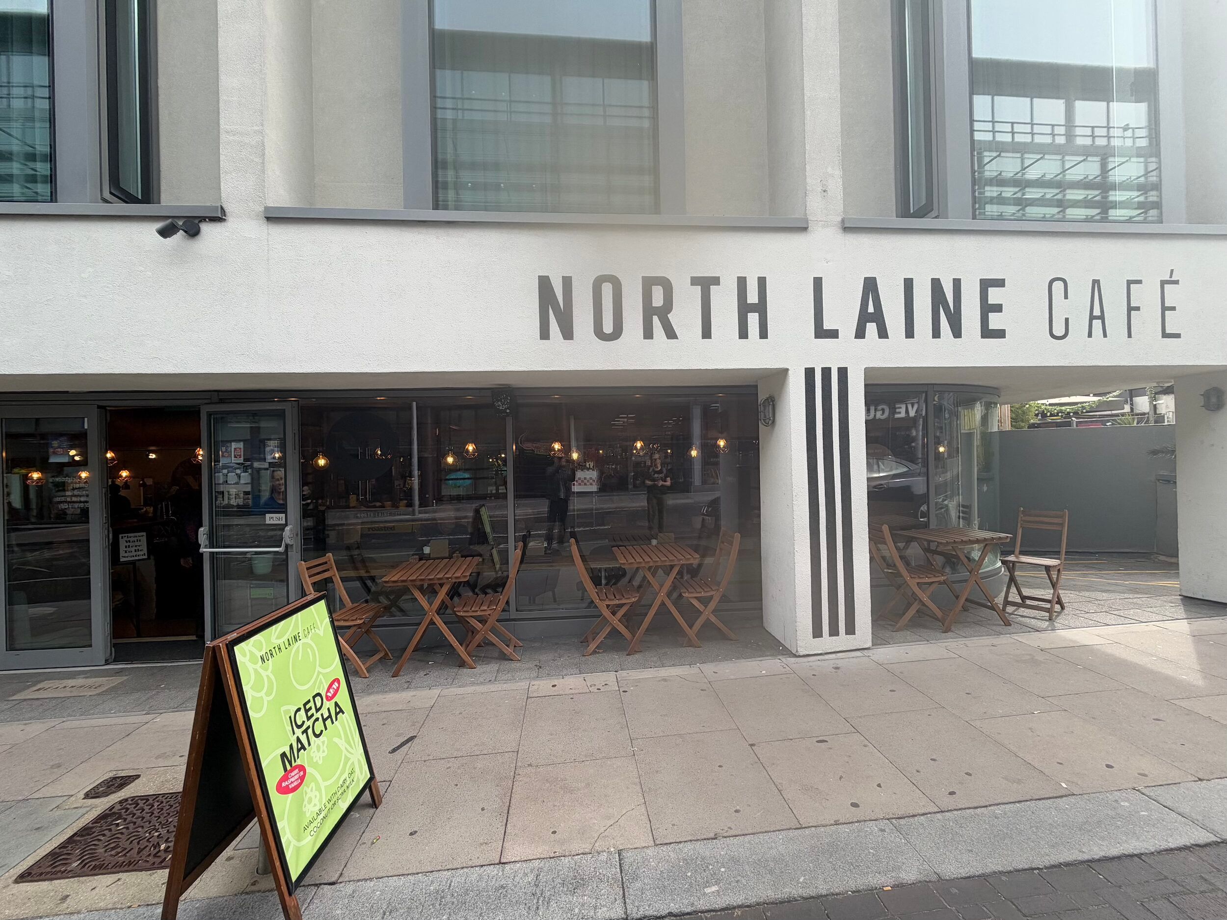 North Laine Café exterior in Brighton, with large windows, wooden tables inside and a chalkboard A-board on the pavement