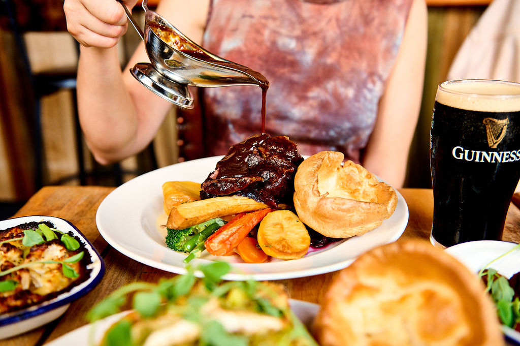 Gravy being poured over a short rib roast with yorkshire pudding